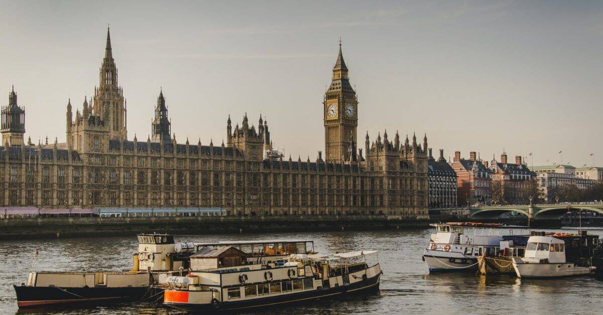 four white boats traveling on river beside Big Ben in London